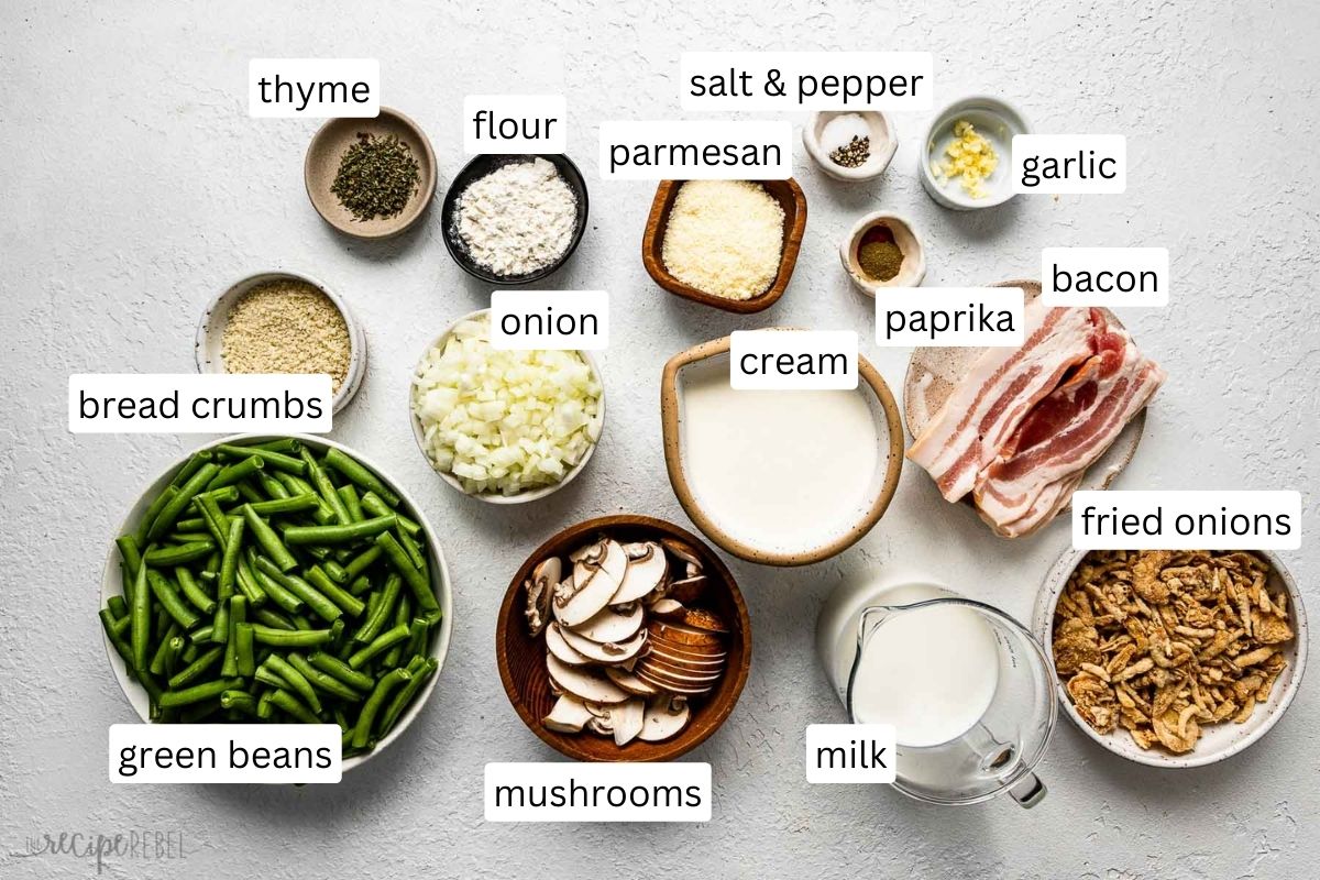 Top view of ingredients for green bean casserole in bowls on white surface.