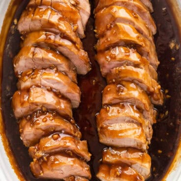 square image of honey garlic pork sliced in white baking dish.