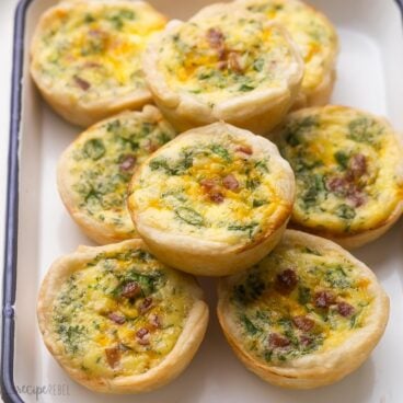 close up of stacked mini quiche in white dish.