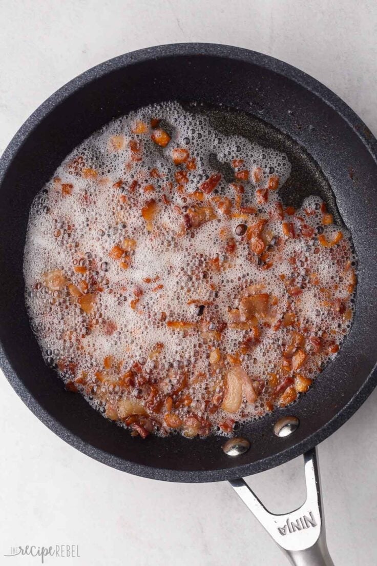 black frying pan filled with cooked bacon and grease.