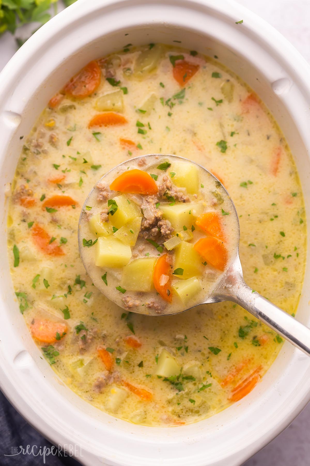 full slow cooker with metal ladle scooping soup out.