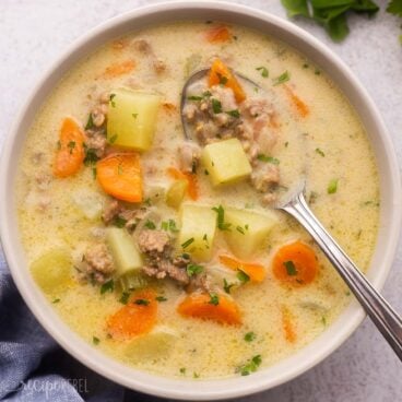 close up of grey bowl and spoon filled with cheeseburger soup.