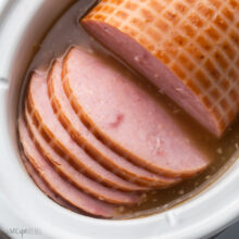 close up of ham slices in white slow cooker.