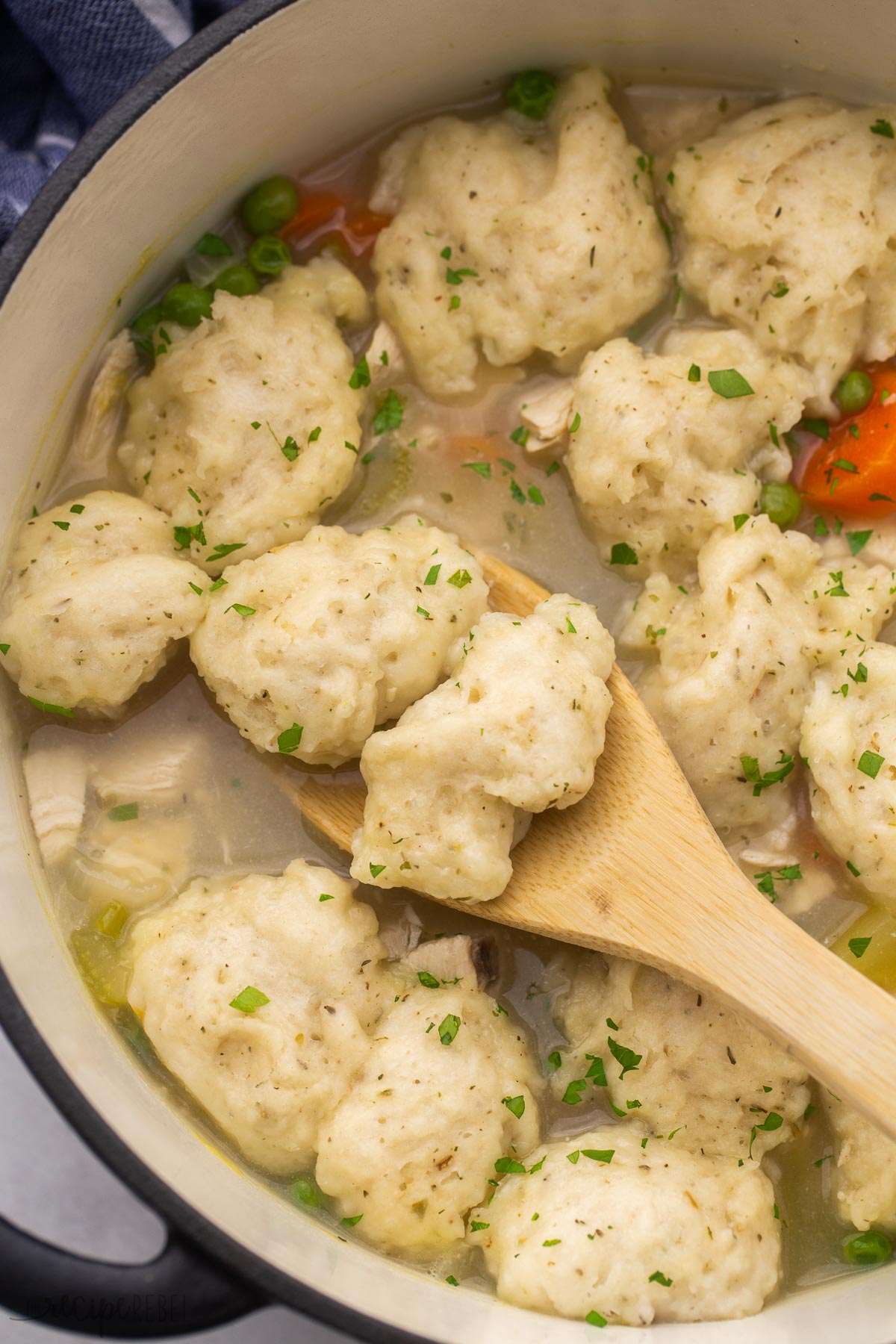 close up of soup dumplings being scooped from pot with wooden ladle.