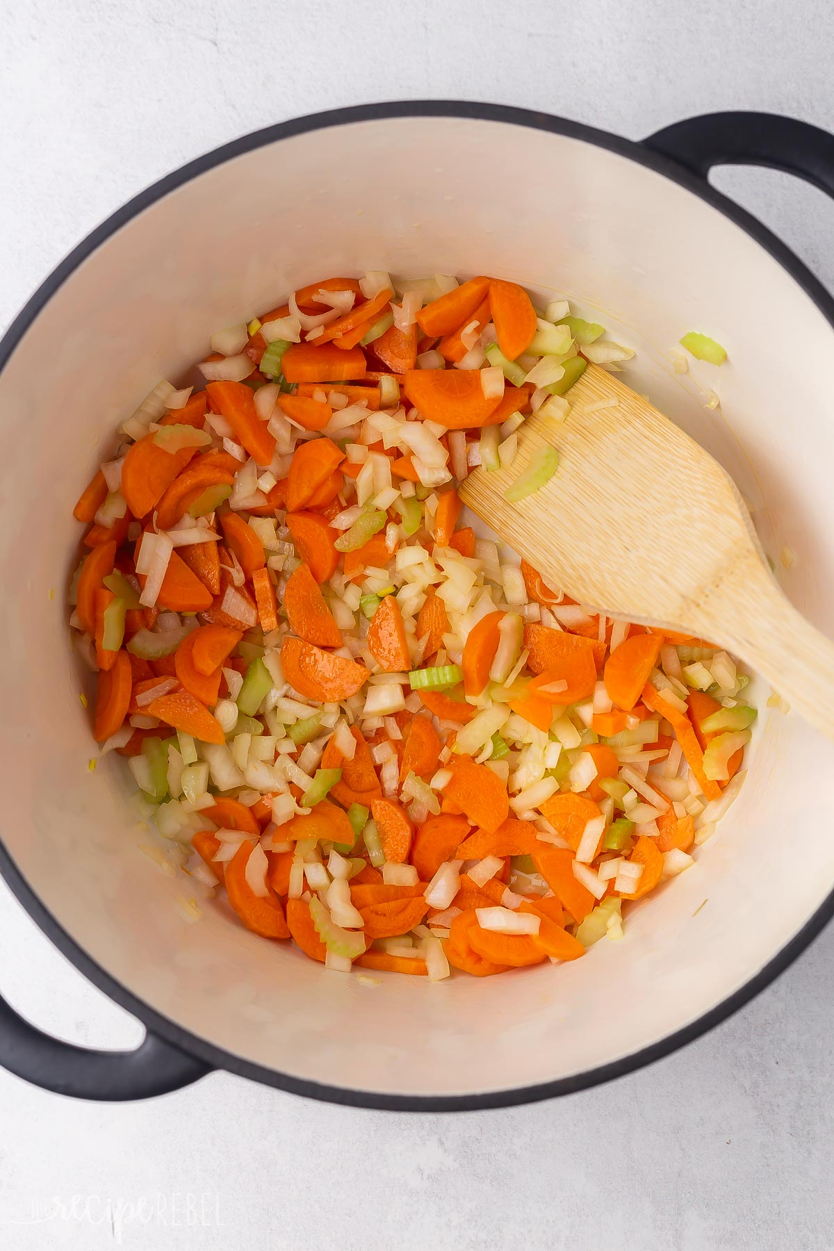 black pot with carrots, celery and onions in it.