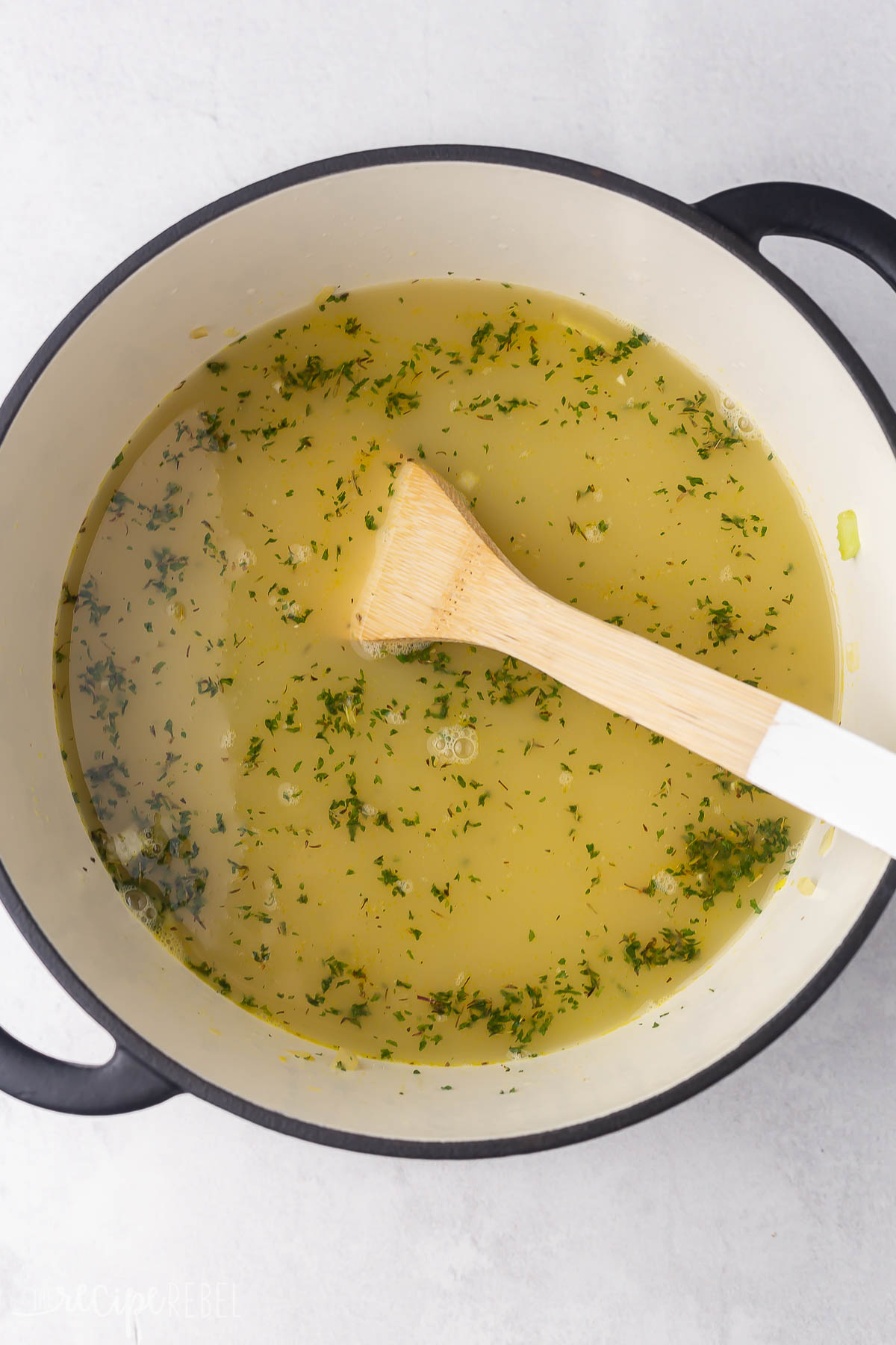 soup pot with broth added and wooden ladle.