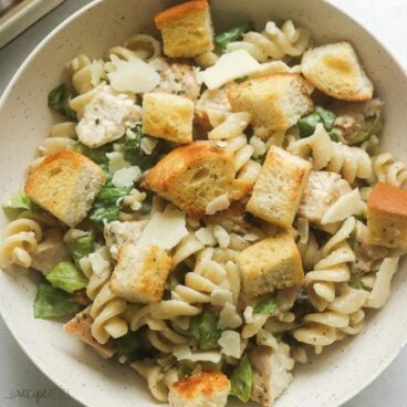 square image of chicken caesar pasta salad in a bowl.