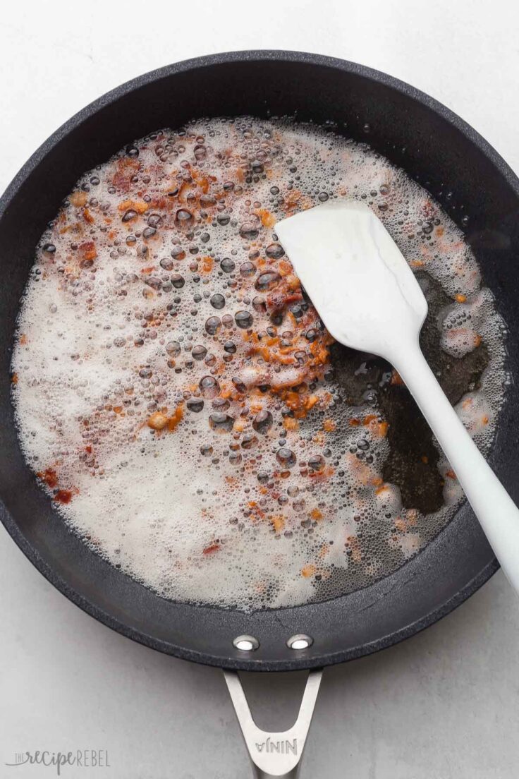 black frying pan with white spatula and chopped bacon cooking.