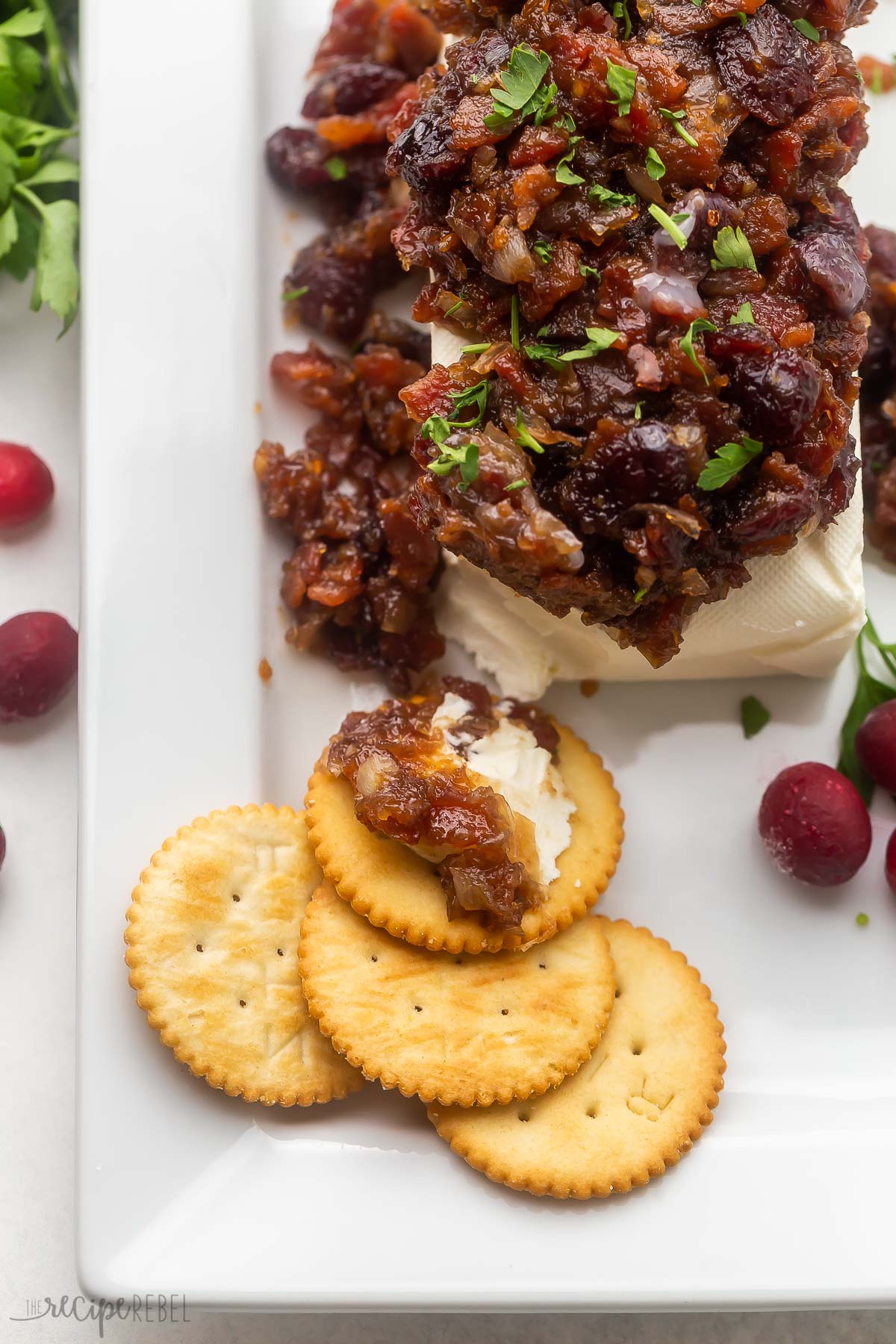 white platter with cranberry bacon cream cheese and crackers.