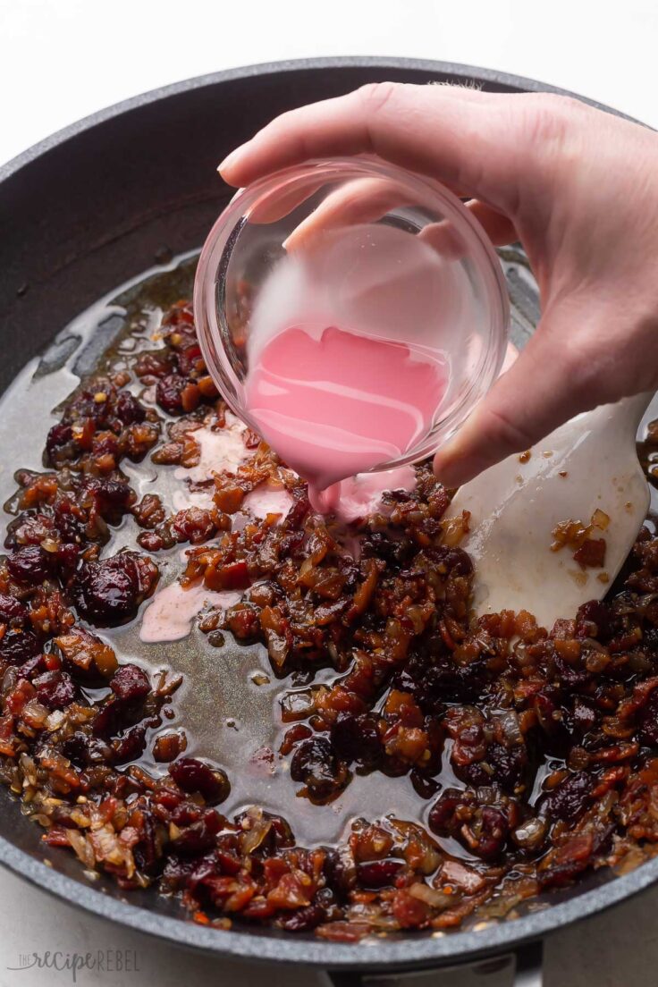 liquid from a glass bowl being poured into black frying pan.