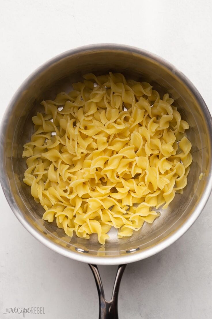 steel pot on grey surface with cooked noodles in it.