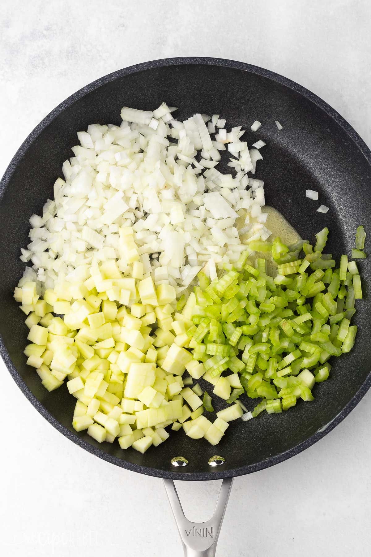 black frying pan full of uncooked vegetables on grey surface.