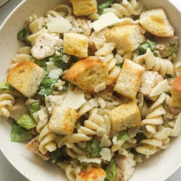 close up image of chicken caesar pasta salad in a bowl.