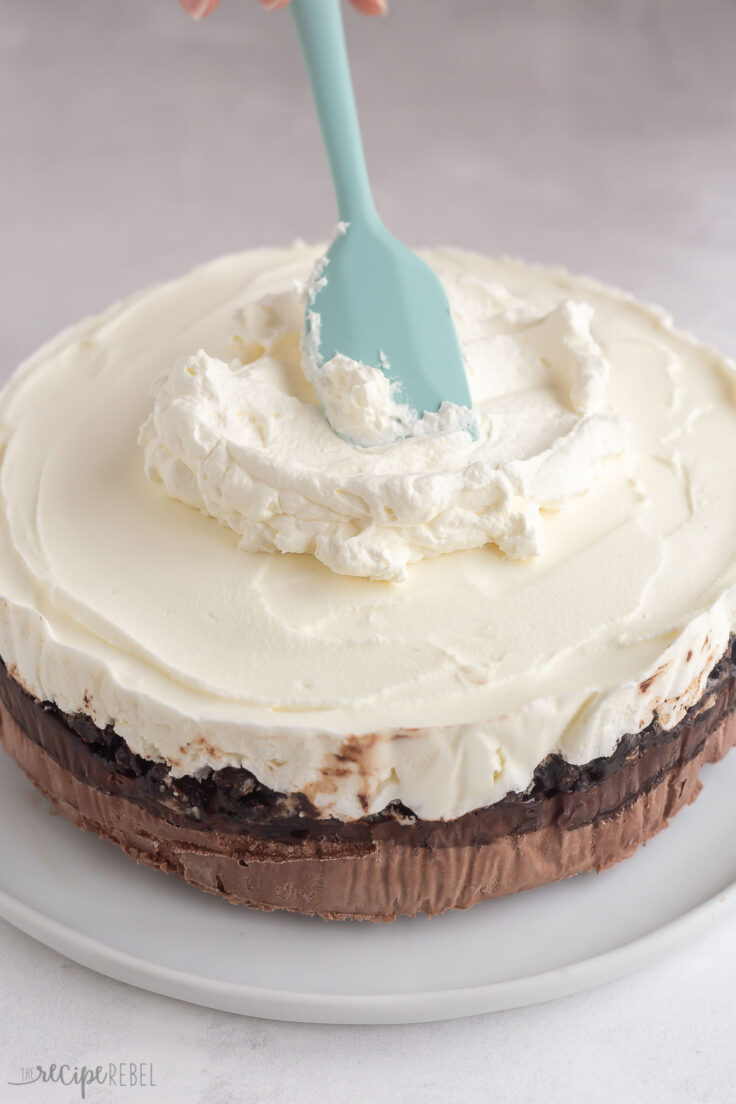 whipped cream being spread onto ice cream cake.