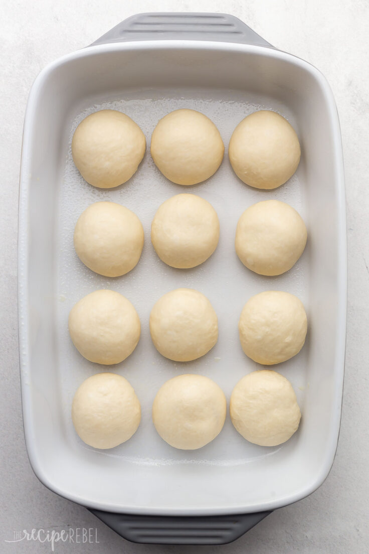 dough formed into balls placed in a white baking dish.