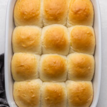 close up of golden baked homemade dinner rolls in pan.