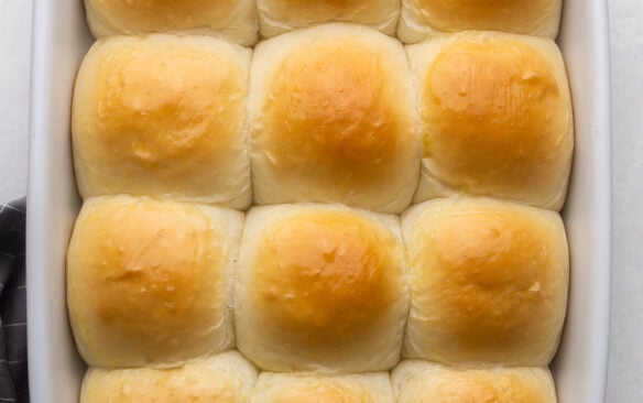 close up of golden baked homemade dinner rolls in pan.