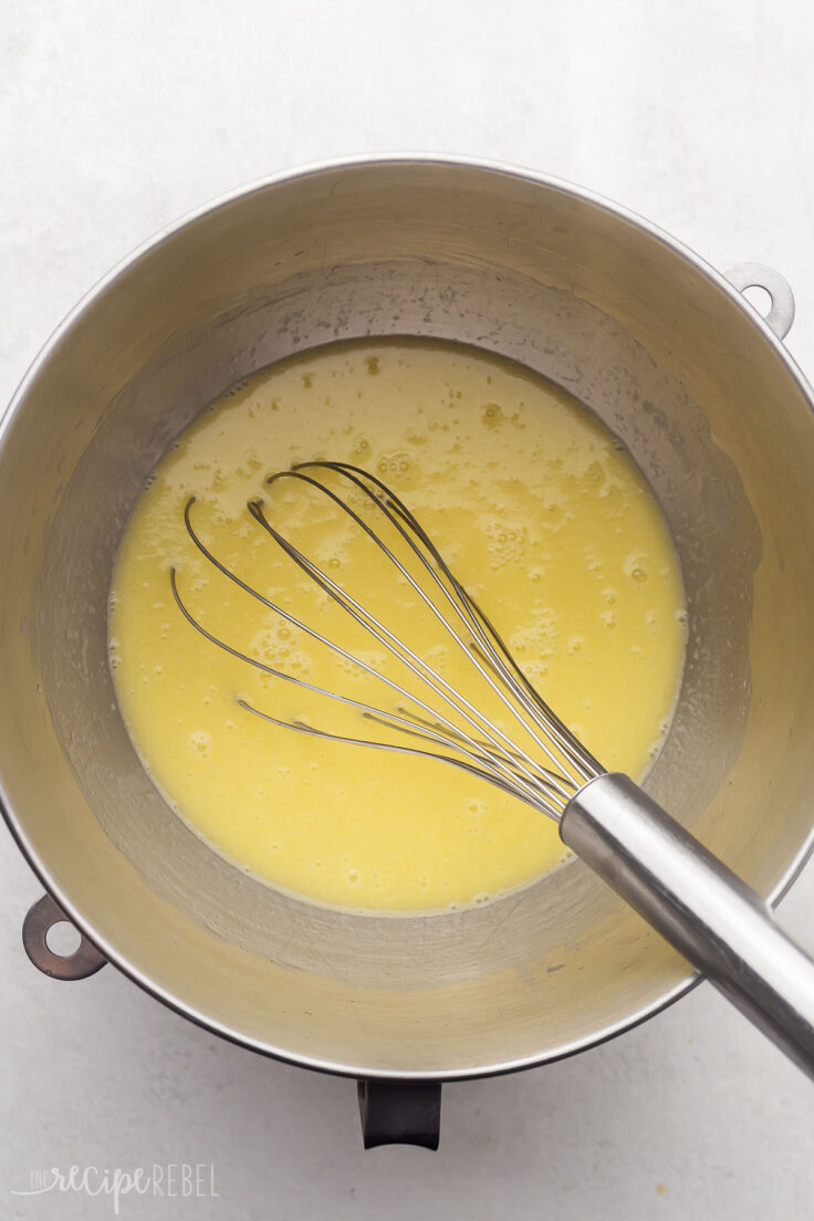 steel mixing bowl on white surface with melted butter in it.