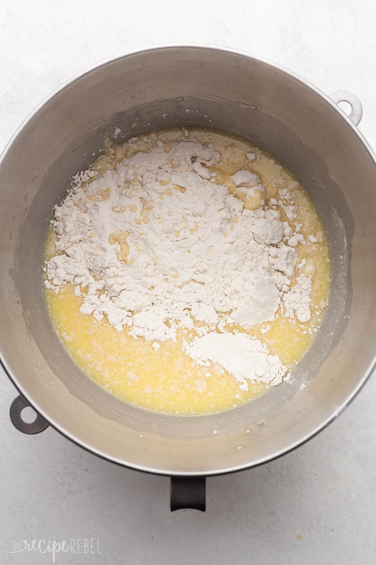 steel mixing bowl with ingredients in and flour added on top.