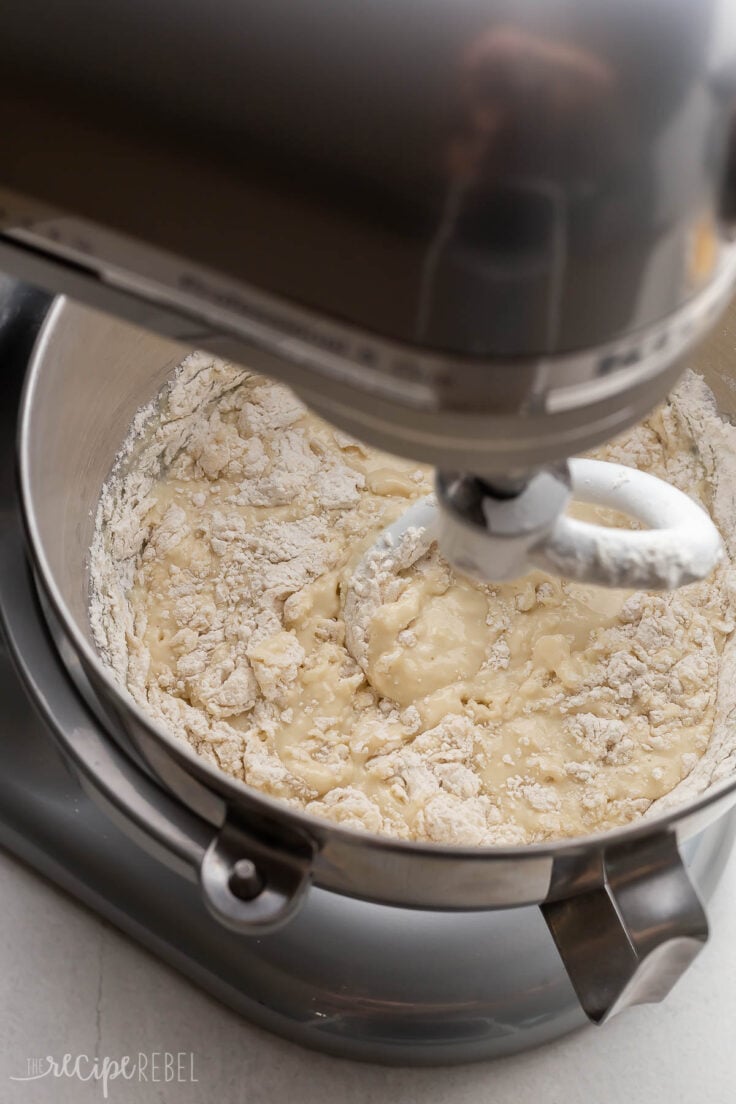 bowl in grey mixer with white hook mixing dough.