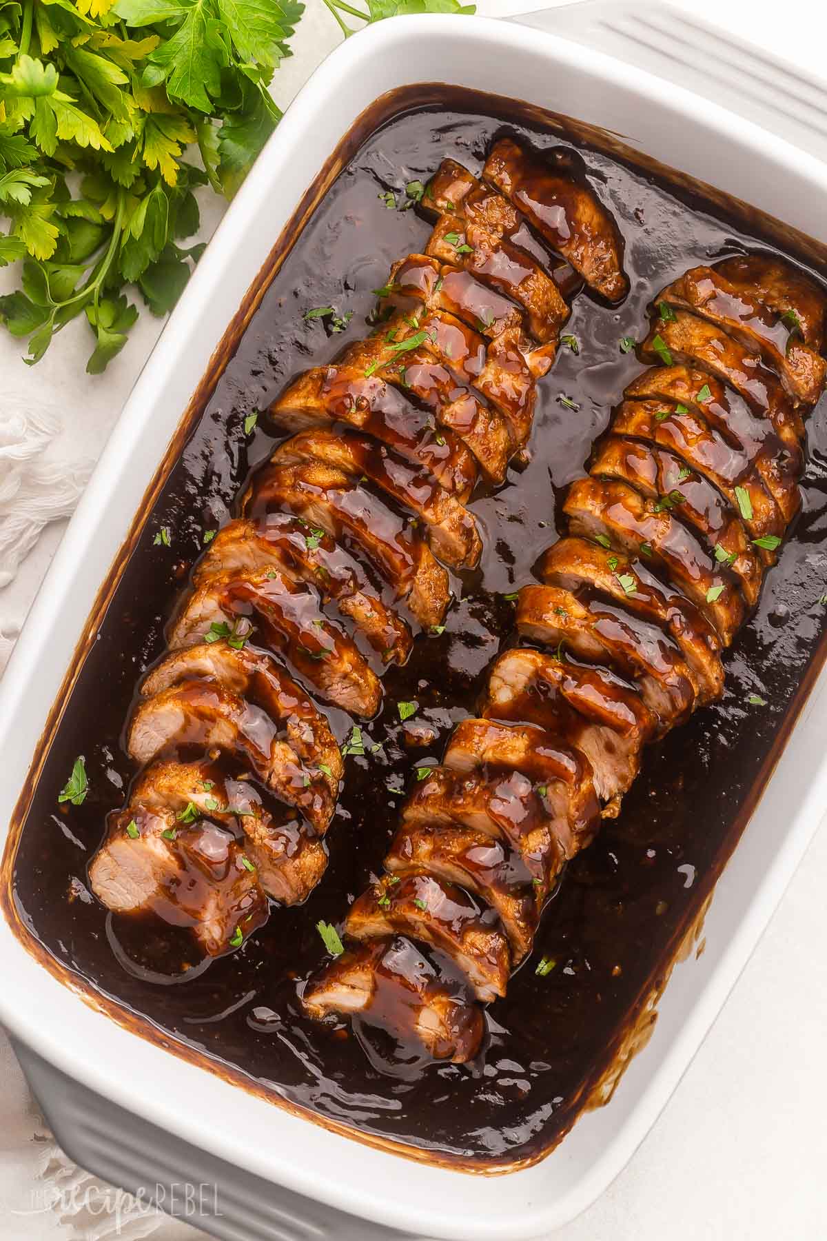 pork tenderloin sliced and in white dish covered in honey balsamic sauce.