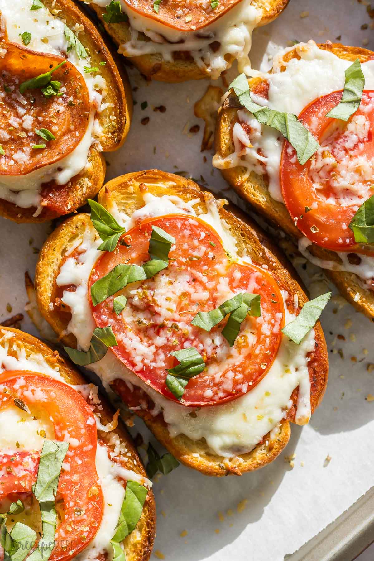 close up image of margherita pizza toast with tomato slice and fresh basil.