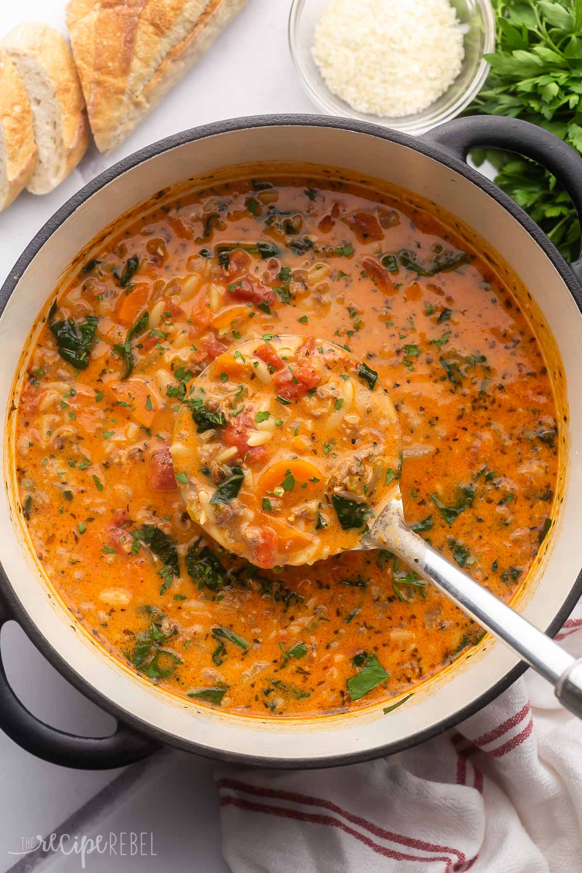 a large pot of soup with a steel ladle scooping out.