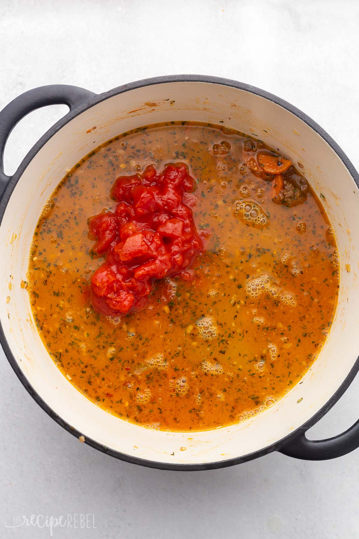 dutch oven full of soup ingredients with diced tomatoes added.