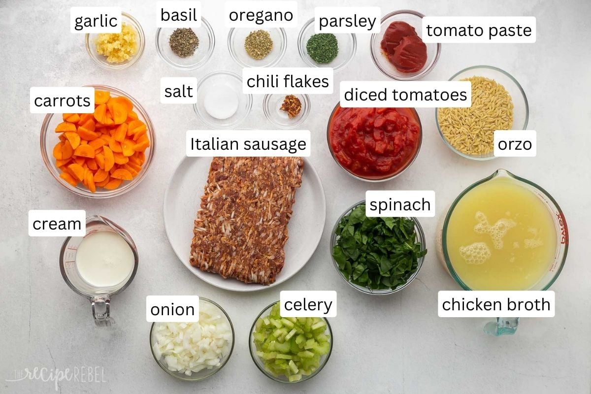 ingredients for sausage orzo soup in glass bowls on grey surface.