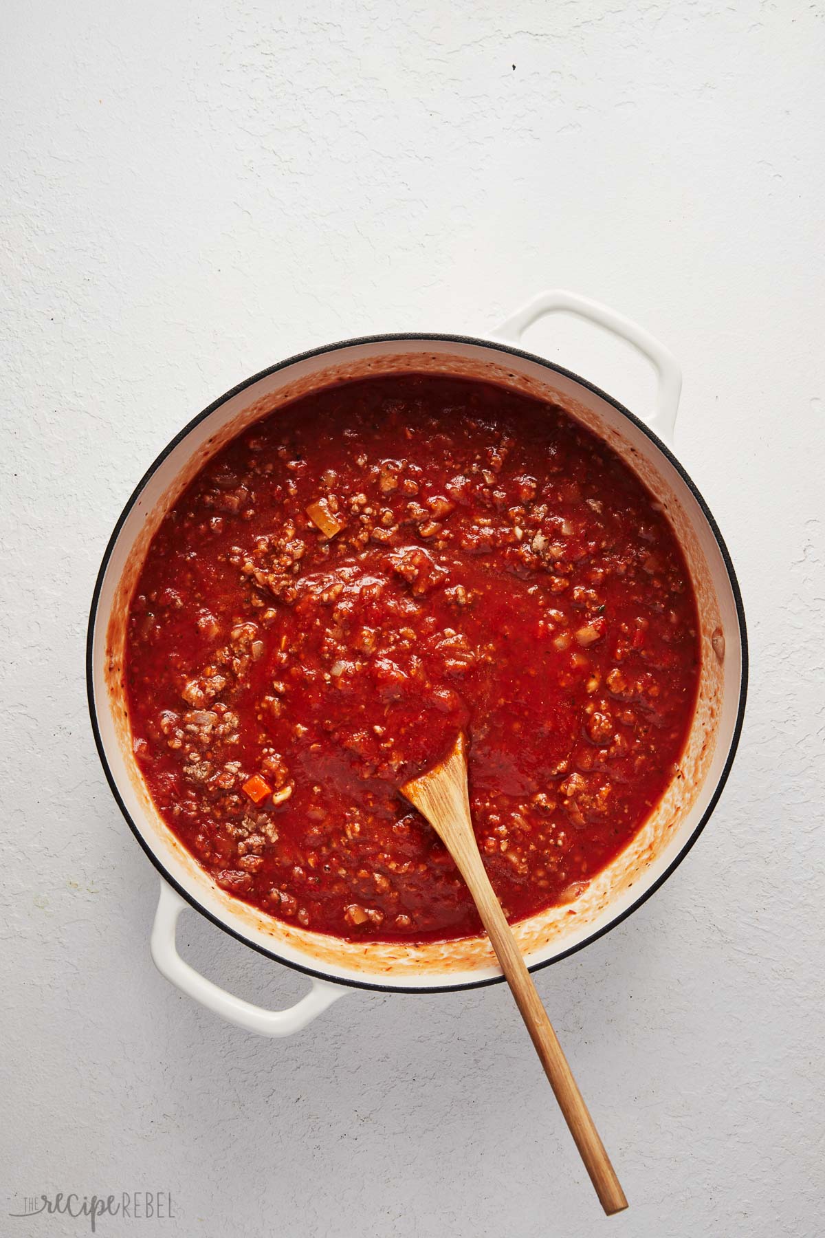 overhead view of cooked meat, onions, and tomato sauce in pot.