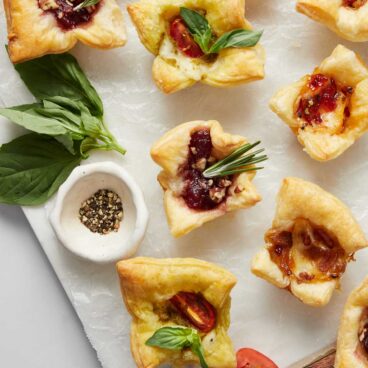 Top view of a baked brie bites on a white surface.