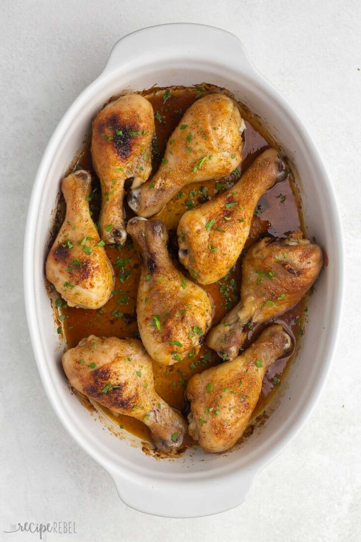 baked chicken drumsticks in white baking dish.
