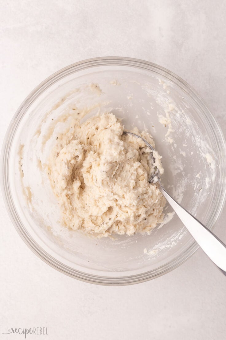 dumpling ingredients mixed in a glass bowl with a spoon.