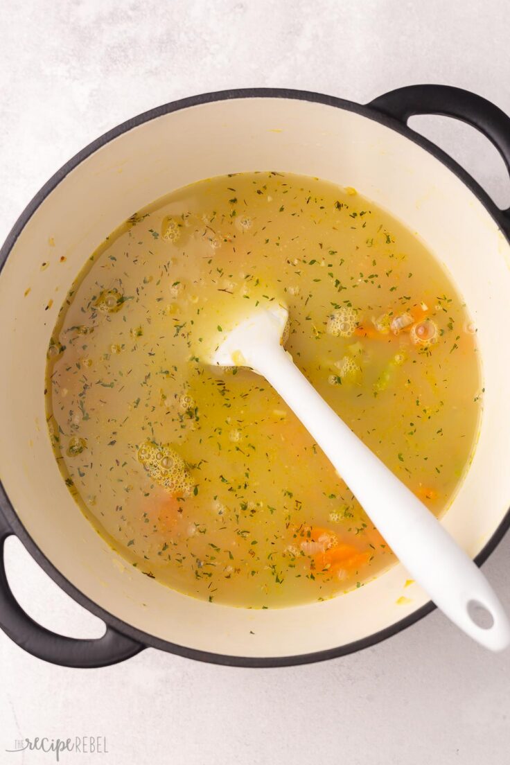 large pot with broth added to sauteed vegetables.