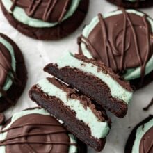 overhead shot of halved chocolate mint cookies on parchment paper.