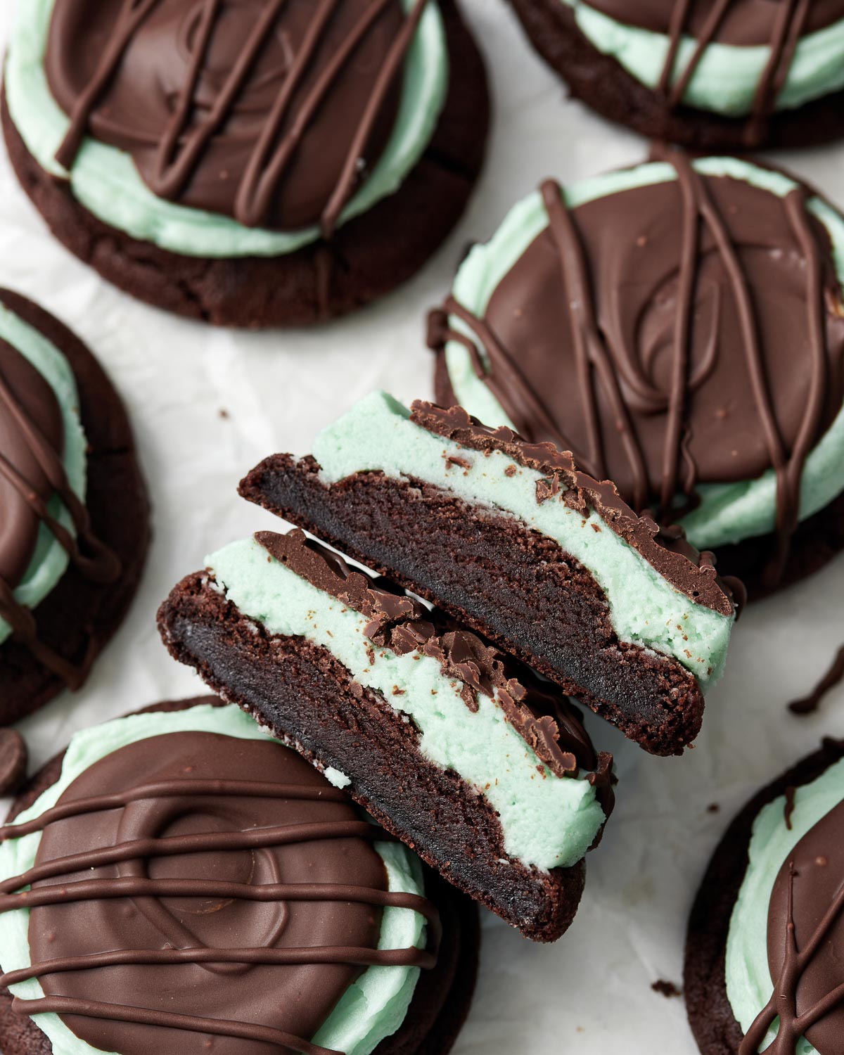 overhead shot of halved chocolate mint cookies on parchment paper.