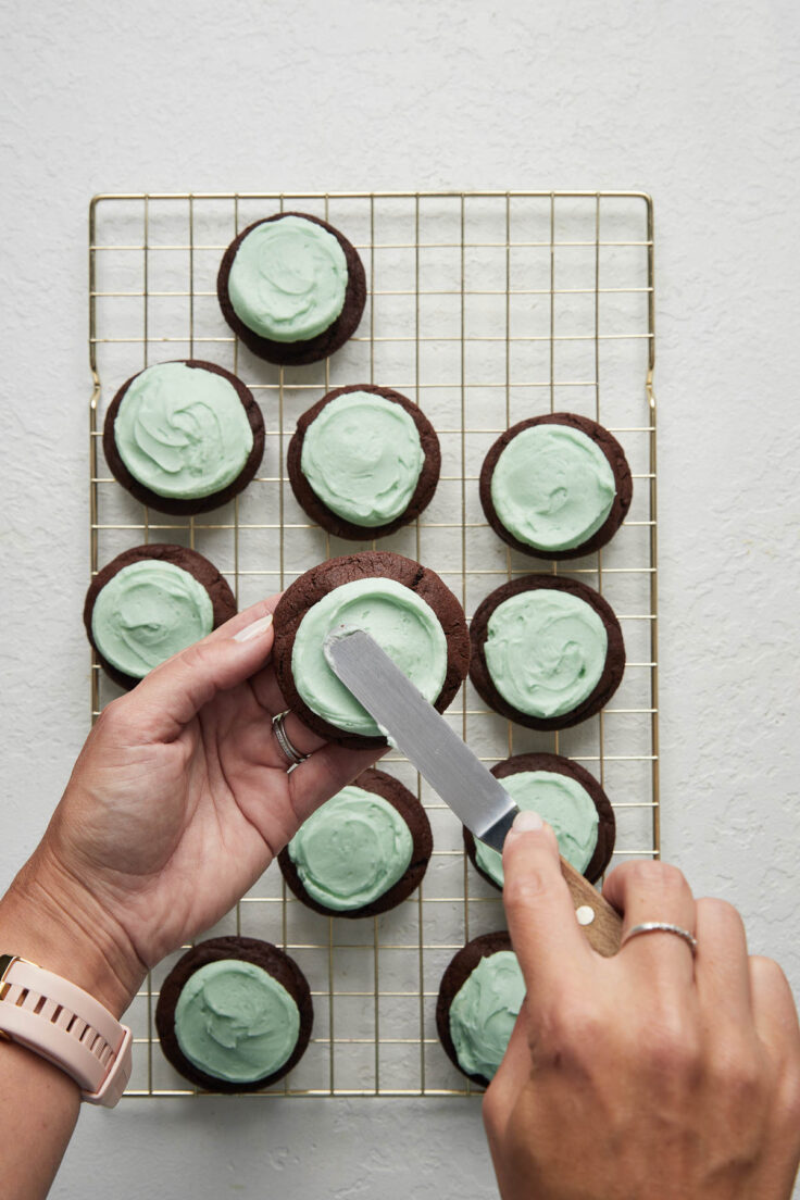 chocolate mint cookies with icing being spread on top.