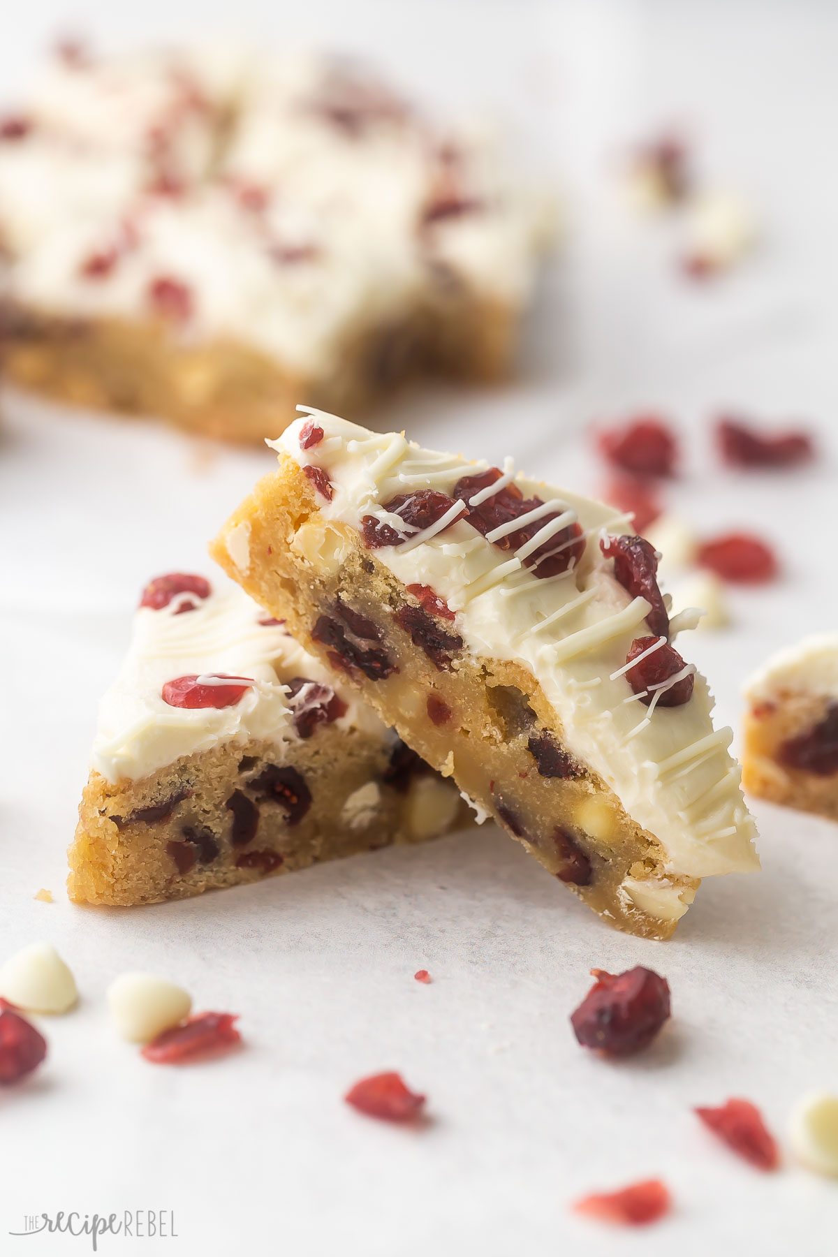 two cranberry bliss bars on a grey surface with more in the background.