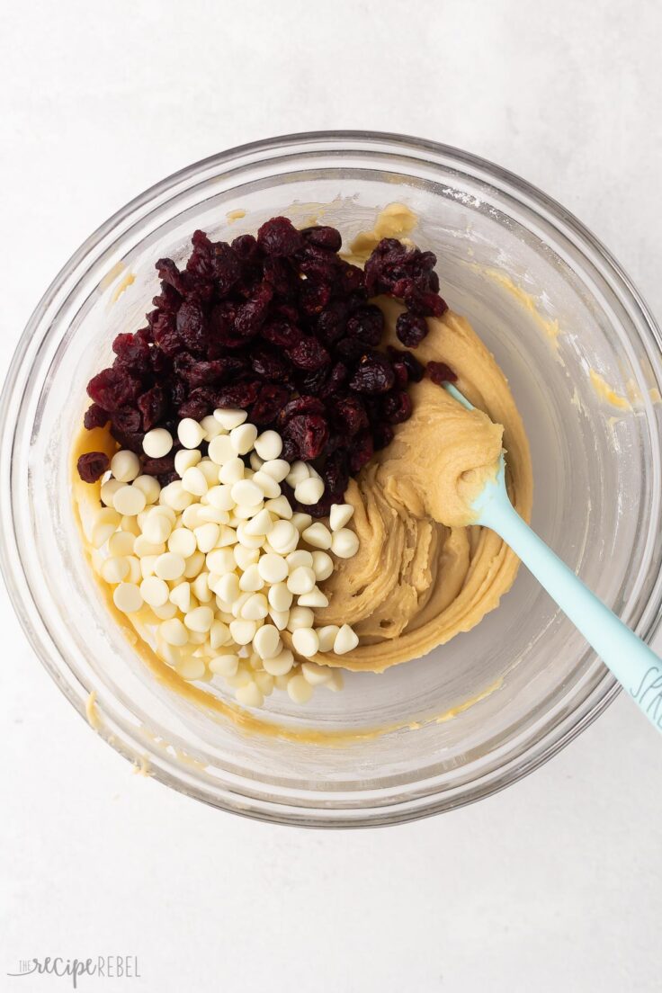 mixed ingredients in glass bowl with cranberries and chocolate chips added on top.