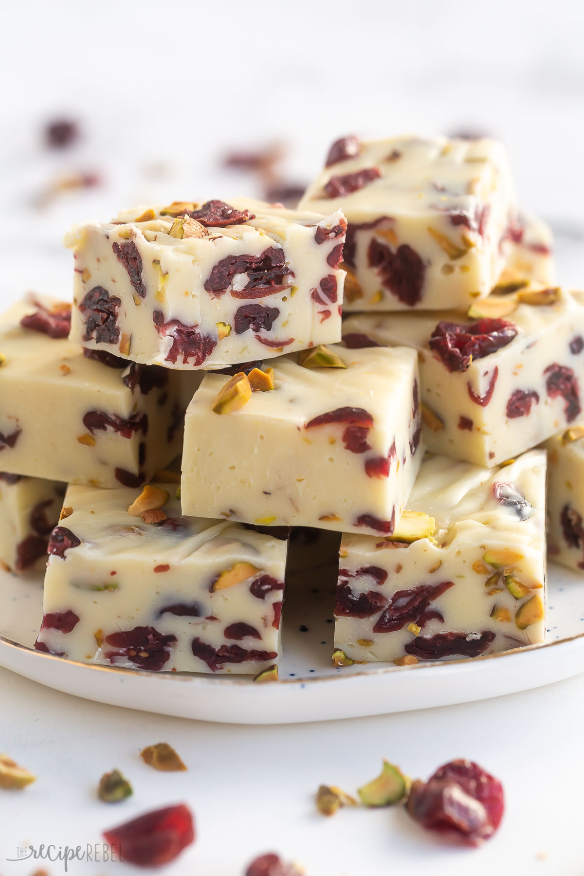 pieces of cranberry white chocolate fudge stacked on a white plate.