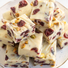 plate full of cranberry white chocolate fudge squares on white surface.
