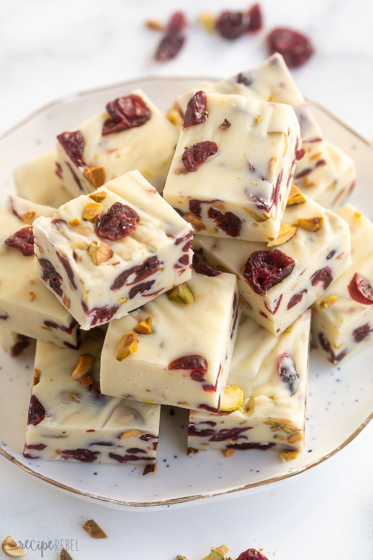 plate full of cranberry white chocolate fudge squares on white surface.