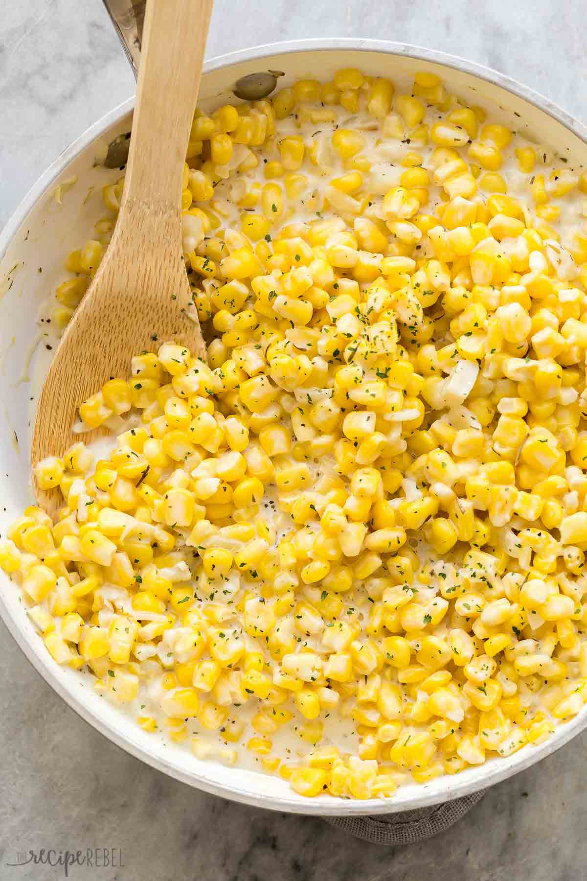 overhead image of homemade creamed corn in white skillet.