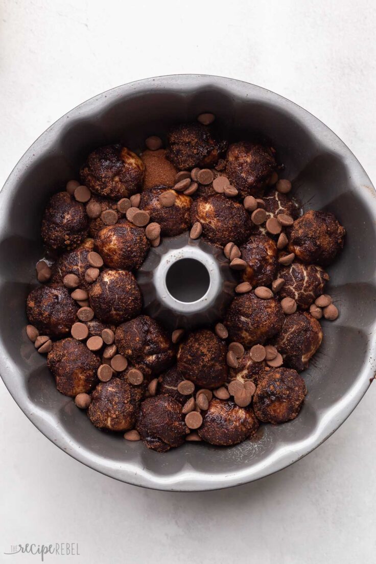 pan filled with chocolate monkey bread and chocolate chips on grey surface.