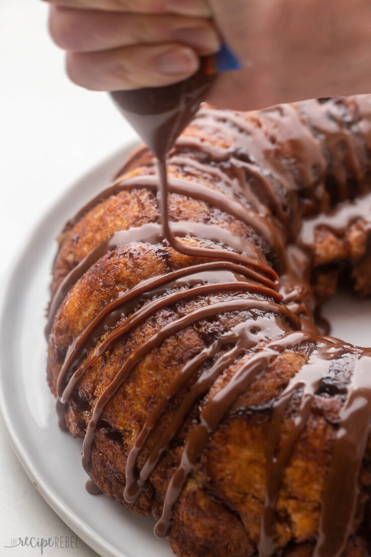 chocolate glaze being drizzled on top of baked monkey bread.