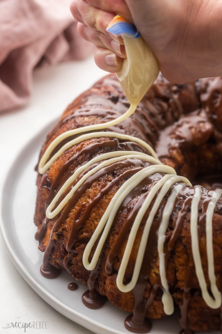 white chocolate glaze being drizzled on top of baked monkey bread.