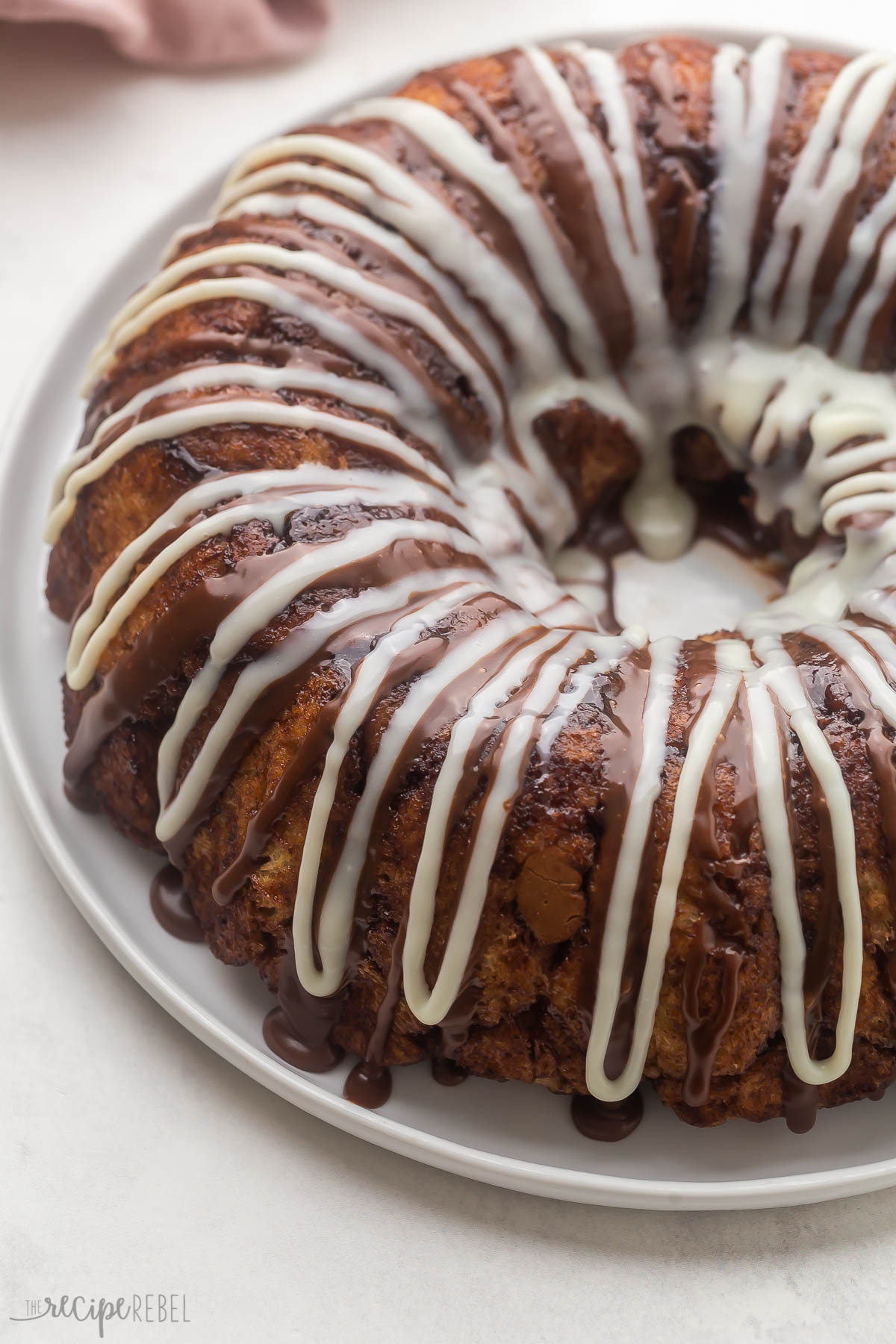 chocolate monkey bread on a white plate topped with chocolate drizzle.