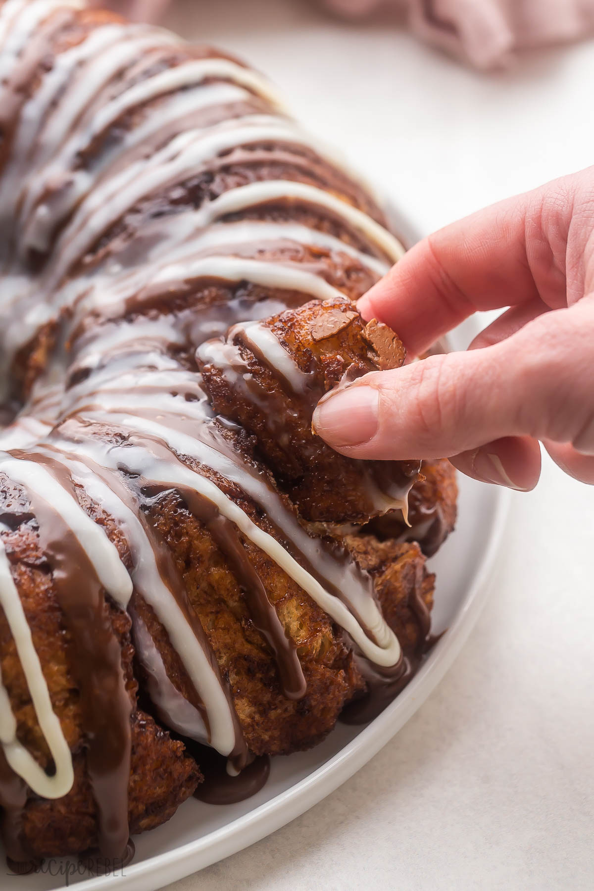 a hand pulling out a piece of chocolate monkey bread.
