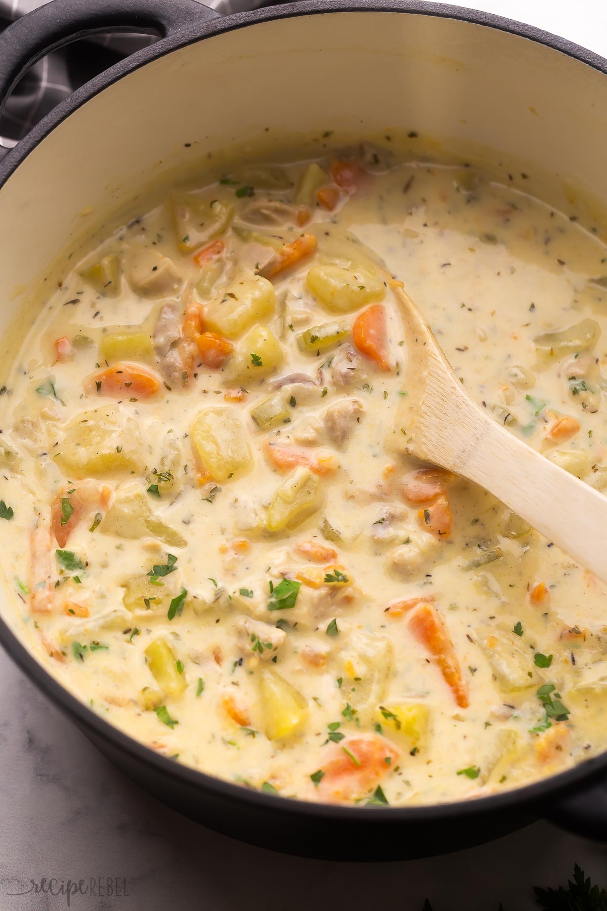 wooden ladle stirring leftover turkey soup in pot.