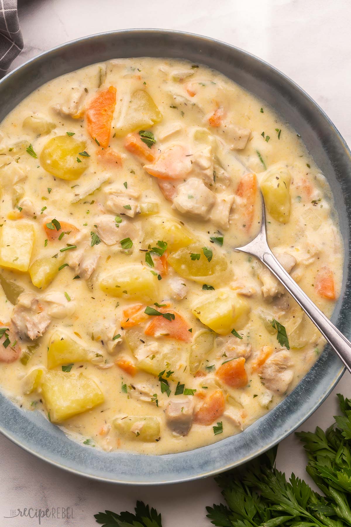 Easy Leftover Turkey Soup is warm and comforting. With tender turkey, loads of vegetables, and a great mix of savory seasonings, it's the perfect way to feed the whole family during the busy holidays! #soup #dinner #recipe | soup recipe | dinner ideas | dinner recipe | leftover turkey recipe | thanksgiving leftovers | creamy soup | healthy soup | a grey bowl full of leftover turkey soup with spoon.